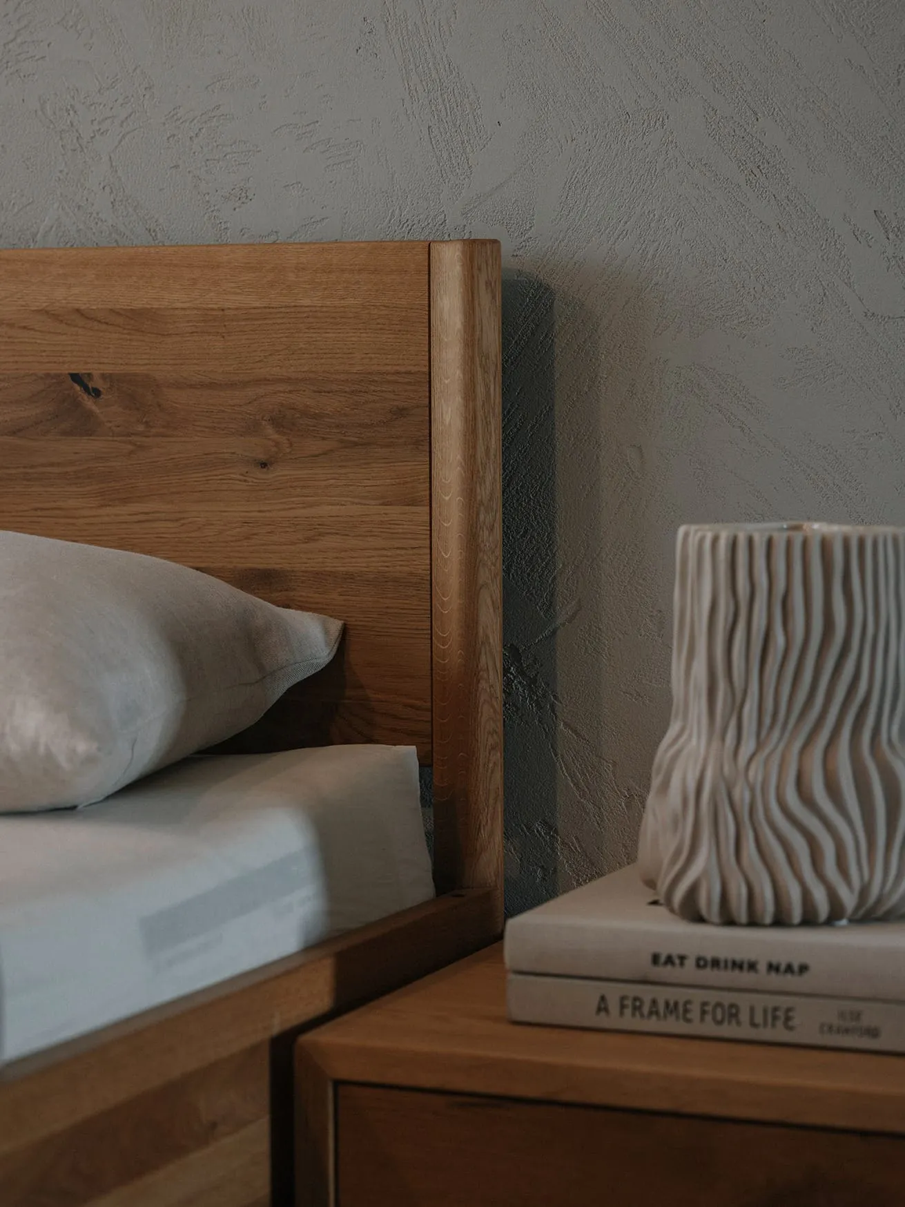 無垢材のベッドとナイトテーブルに置かれた本